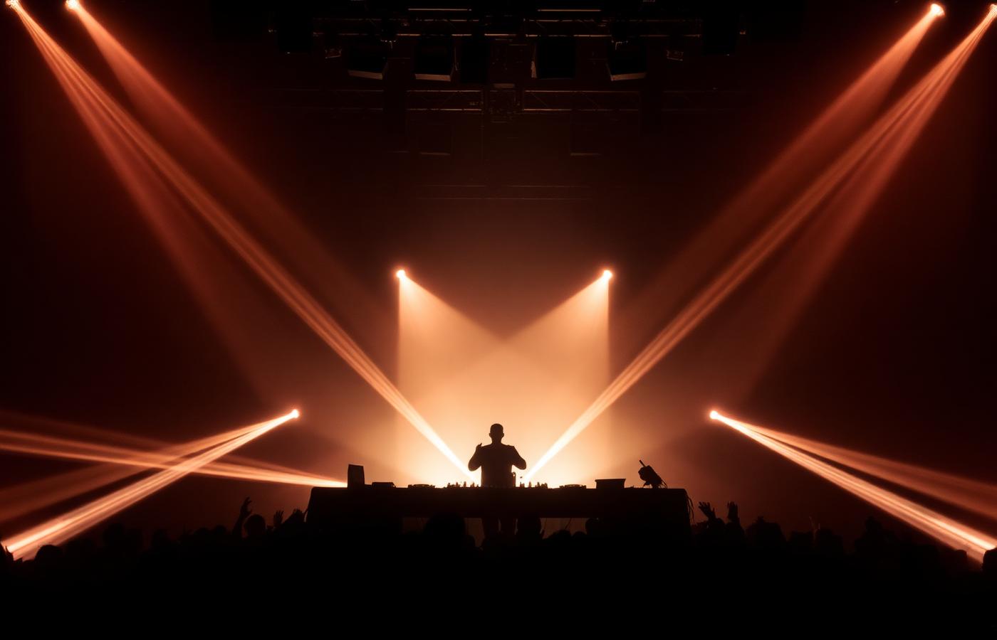 DJ silhouette behind the booth with laser lighting
